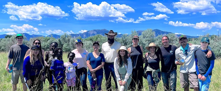 FLOWS group gathering and smiling in front of mountain views at local regenerative farm